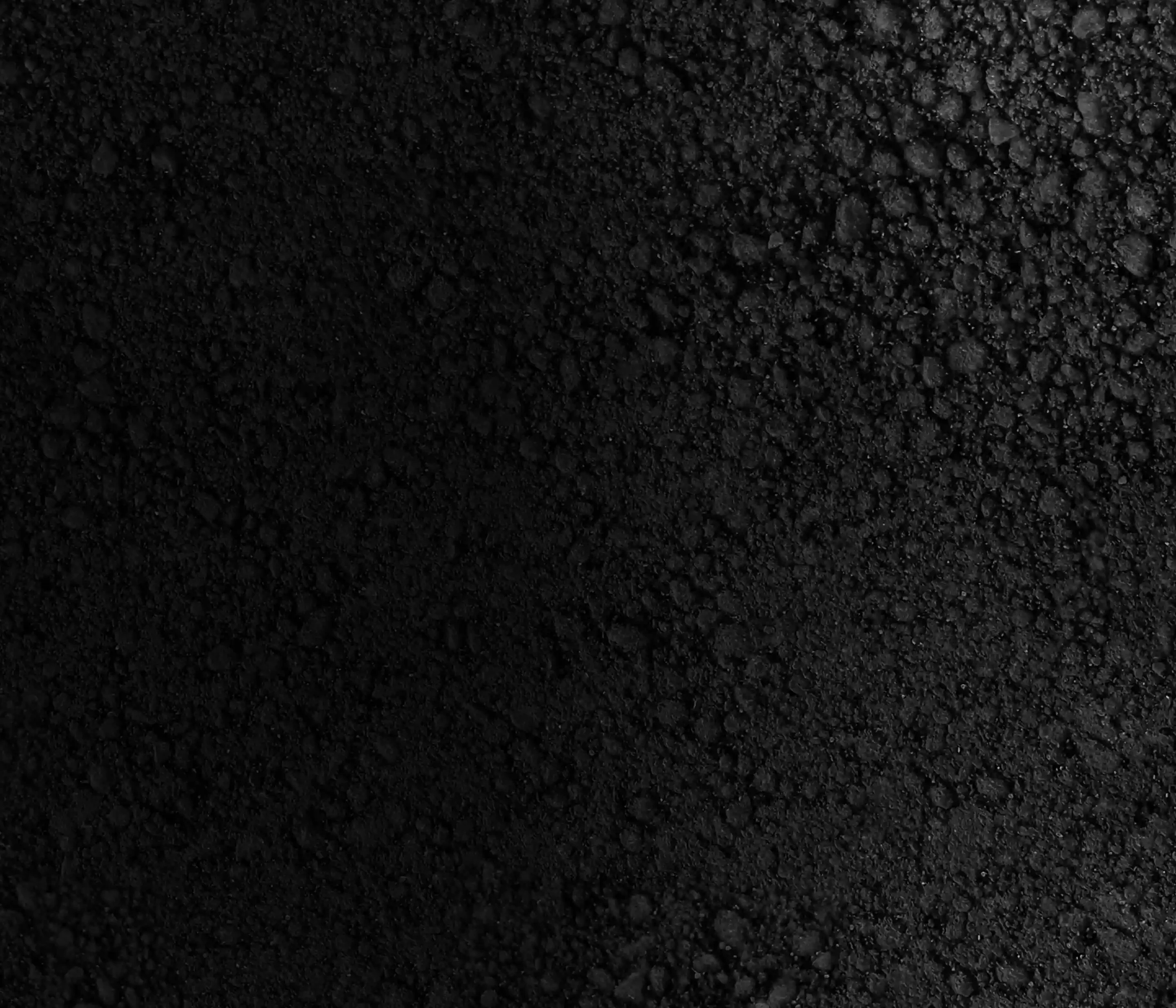Close-up of a textured black surface, featuring various sizes of coarse 
		    particles and a matte finish, creating a rich, dark appearance.